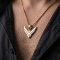 Load image into Gallery viewer, Rose gold plated House Atreides pendant worn on the chest, showcasing the stylized hawk symbol, layered geometric details, and distinctive Dune inspired aesthetic.