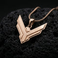 Load image into Gallery viewer, Rose gold plated House Atreides necklace displayed on textured volcanic stone, showcasing the stylized hawk symbol, layered edges, and distinctive science fiction aesthetic.