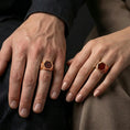 Load image into Gallery viewer, A red onyx signet ring in a rose gold plated finish worn on a finger in a clean lifestyle close-up.