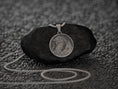 Load image into Gallery viewer, Close-up of engraved dragon pendant resting on dark stone,