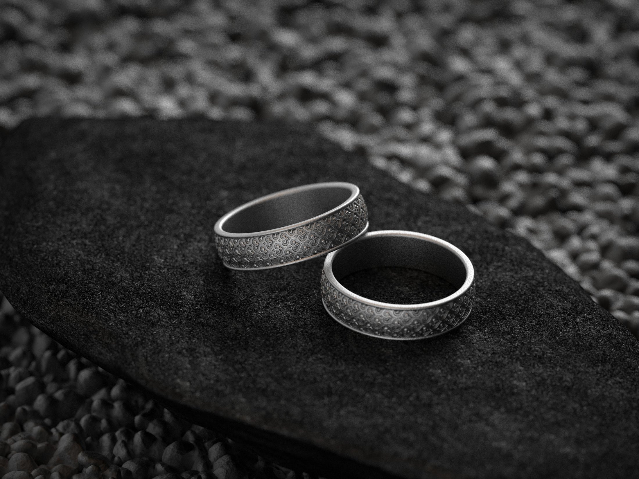 Matching oxidized floral wedding bands on dark background
