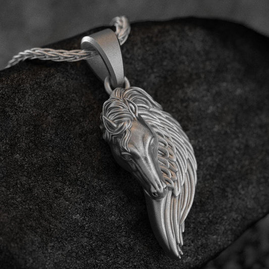 Oxidized silver pegasus wing horse necklace on dark stone background,