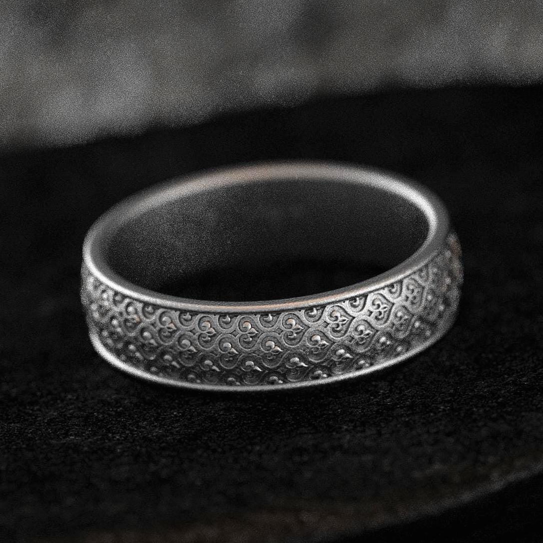 Oxidized silver wedding band with braided floral motif on black stone