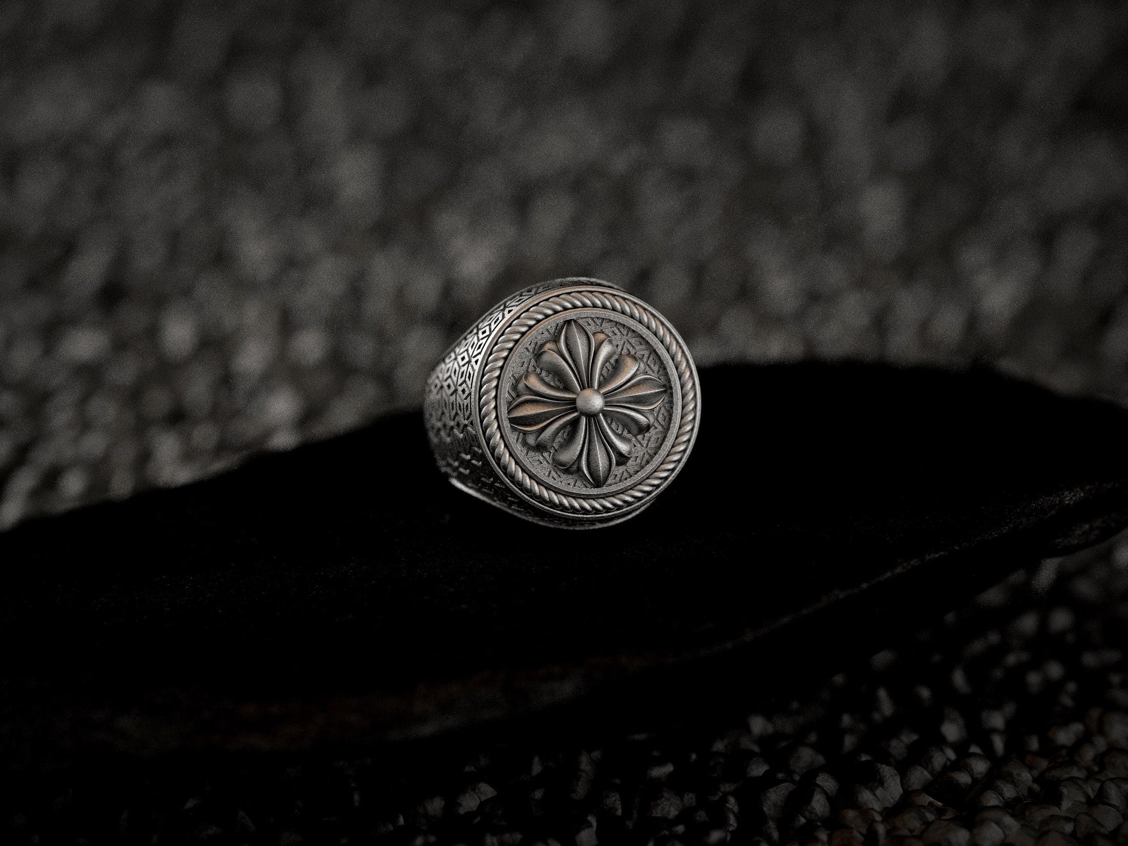 Bold round crest ring showing intricate side textures in silver,