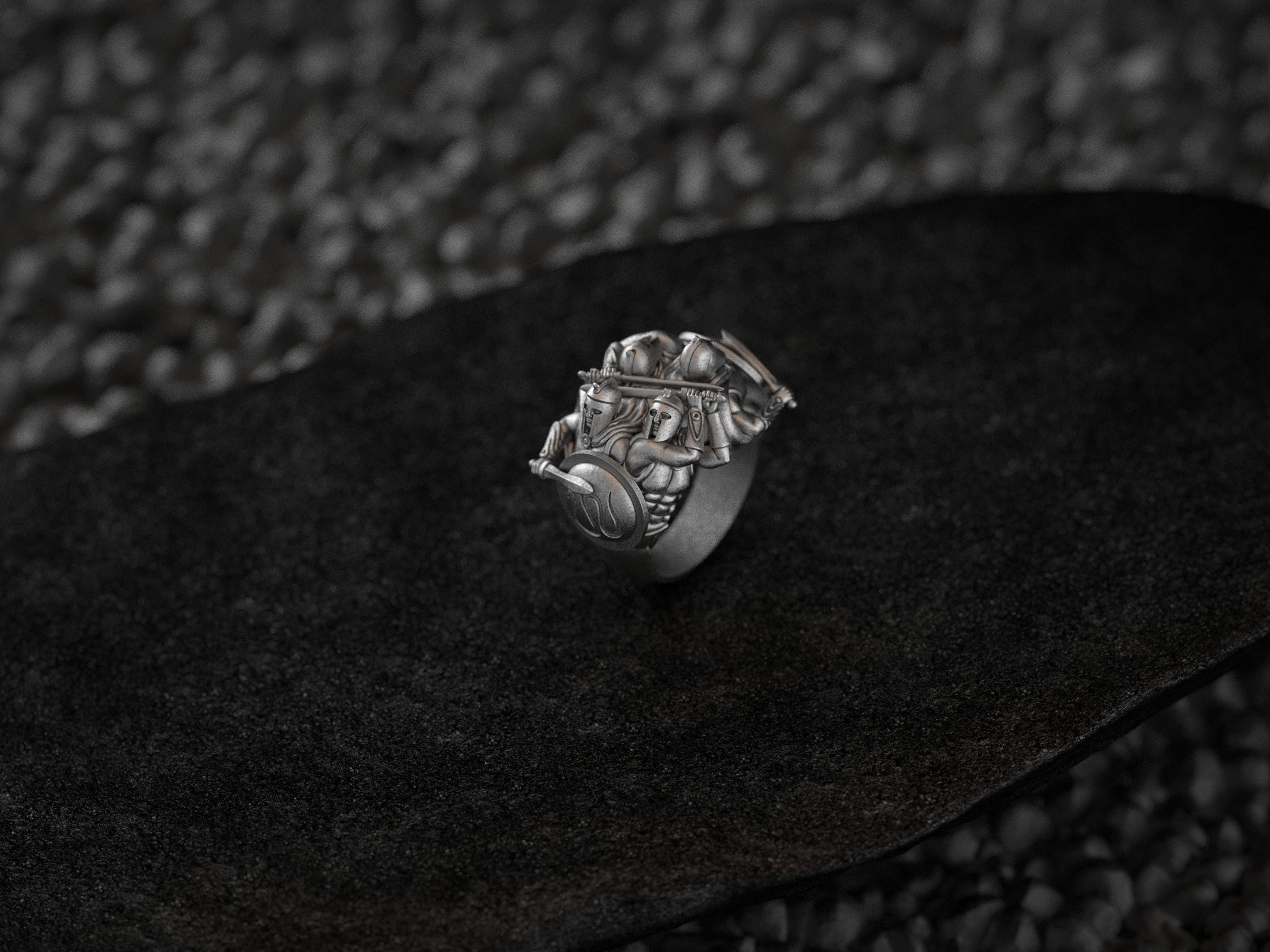 Detailed view of carved Greek warrior helmets, shields, and spears on silver ring