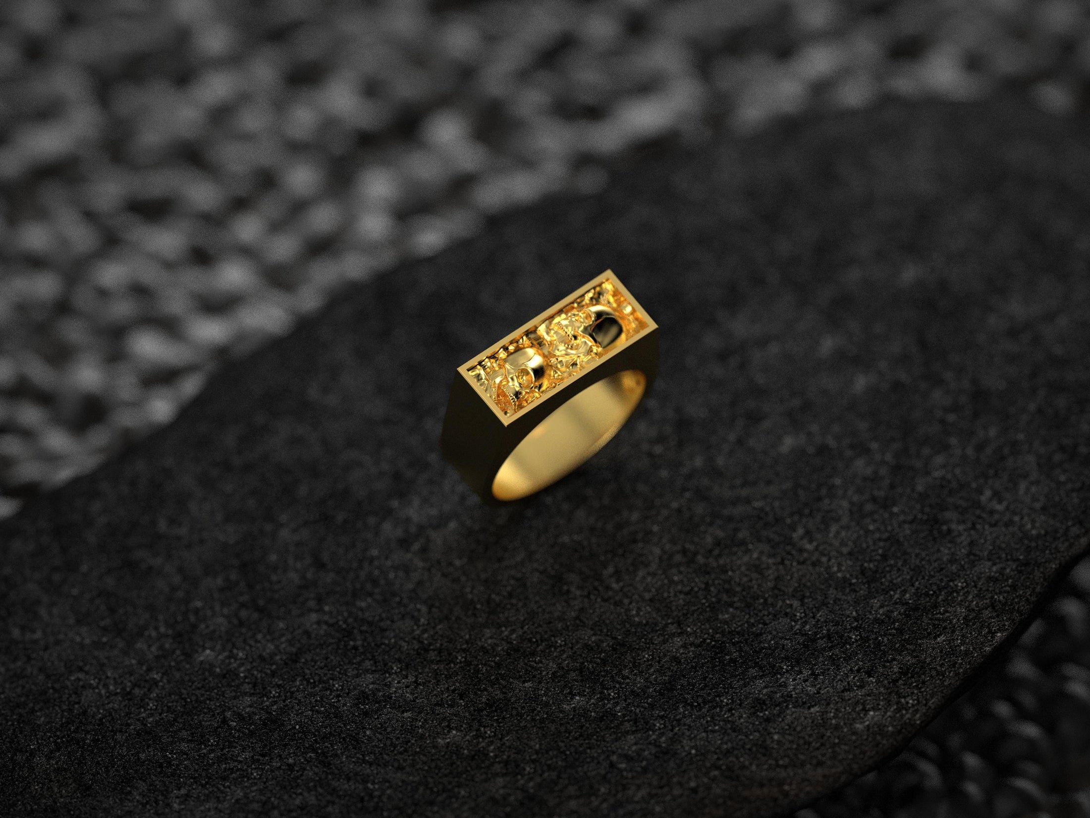 Front view of the yellow gold–plated version, emphasizing the dual skull motifs against the ornate relief.