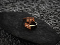 Load image into Gallery viewer, Angled shot of the rose-gold plated ring, accentuating the twin skull carvings and thin bezel border.