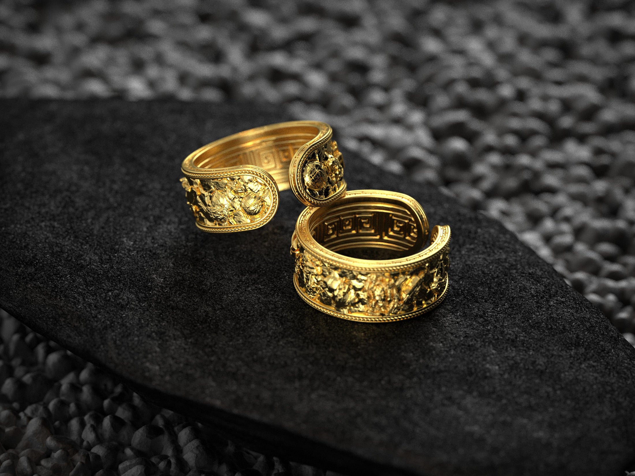 Trio of mythology rings in gold, silver, and rose finishes on textured background