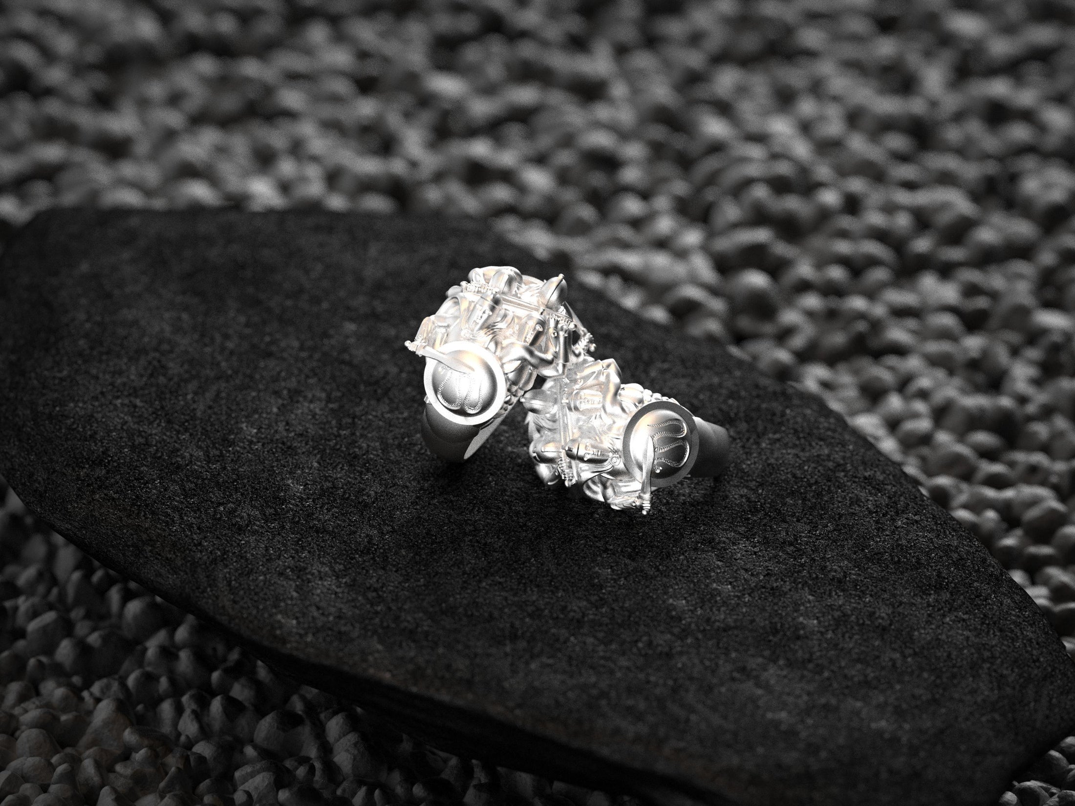 “Polished silver double Spartan rings viewed from behind on dark stone, highlighting the hoop band and sculpted hoplite backs.”