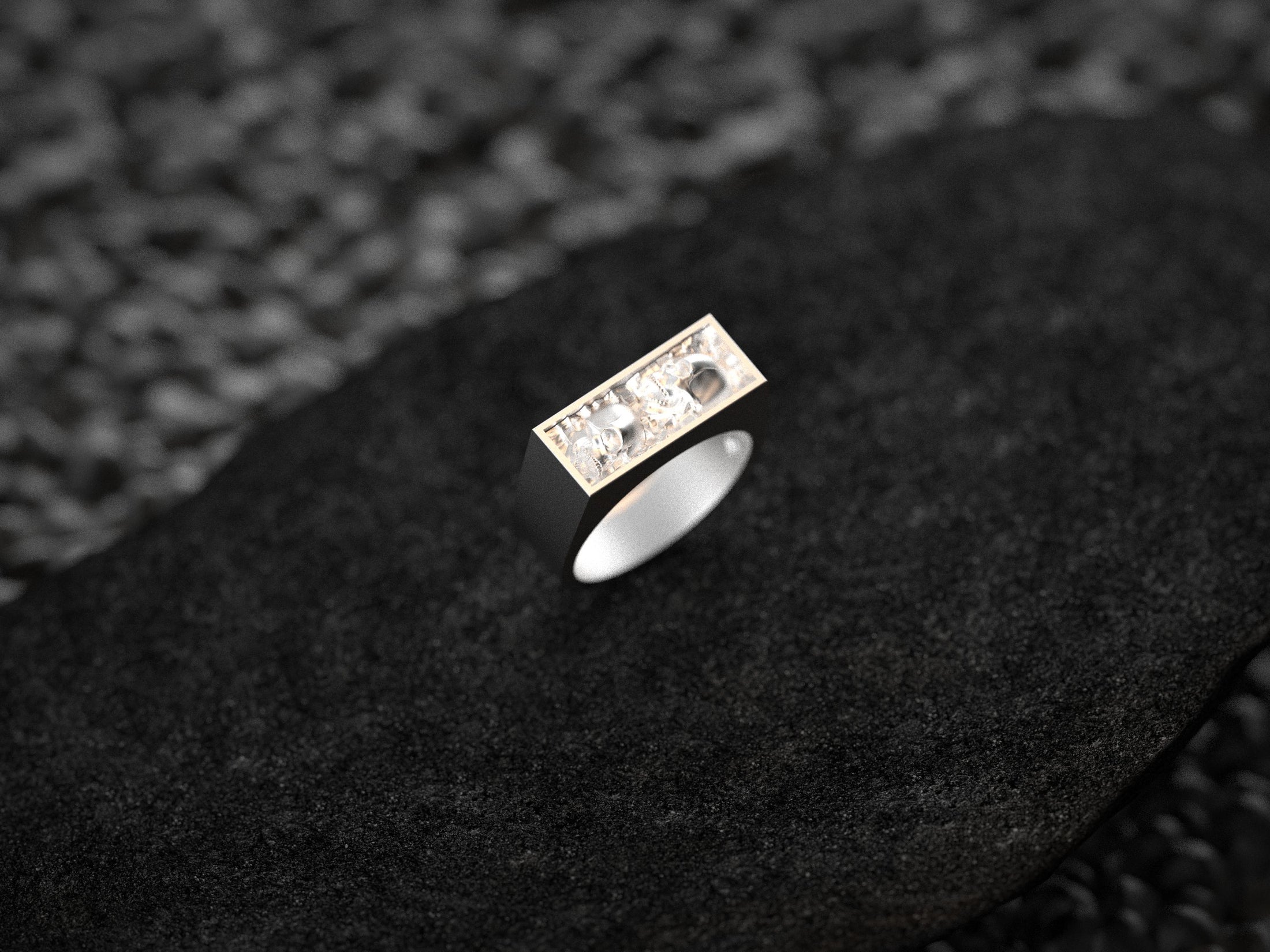 Close-up macro of the twin skulls in sterling silver, highlighting the carved eye sockets and textured background.
