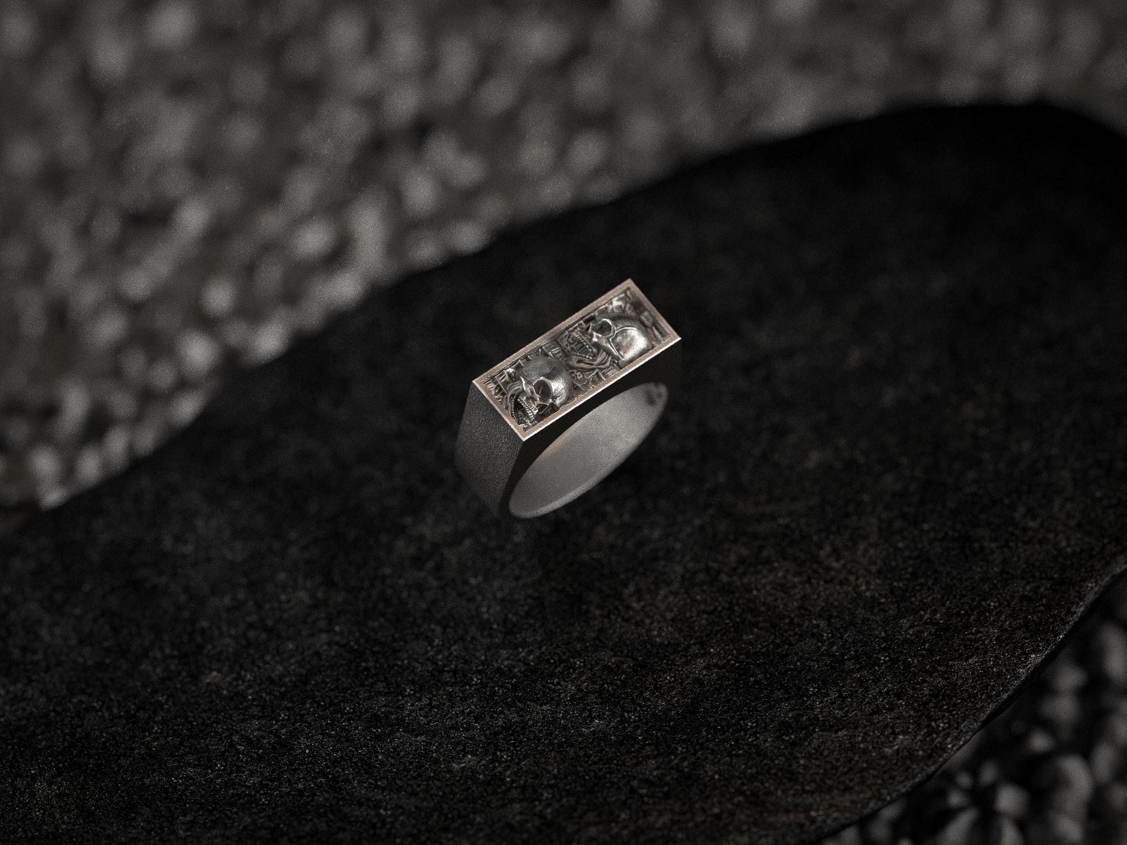 Close-up macro of the twin skulls in sterling silver, highlighting the carved eye sockets and textured background.