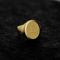 Bild in Galerie-Betrachter laden, May include: A gold signet ring with a textured, circular top featuring an engraved design. The ring has a classic style and is displayed on a dark gray surface.