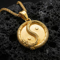 Load image into Gallery viewer, Gold plated yin yang dragon pendant necklace symbolizing balance on volcanic stone surface