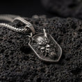 Load image into Gallery viewer, Oxidized oriental demon dragon dog tag pendant necklace photographed on volcanic rock with deep engraved oni mask detail