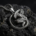 Load image into Gallery viewer, Polished silver xenomorph alien pendant necklace displayed on volcanic stone background with sharp sculpted relief