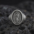 Load image into Gallery viewer, Oxidized Our Lady of Guadalupe signet ring in sterling silver photographed on volcanic rock background