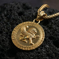 Load image into Gallery viewer, Gold plated winged lion pendant necklace photographed on volcanic rock with detailed mythical griffin style relief and Greek key border