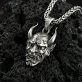 Load image into Gallery viewer, Oxidized oni mask pendant necklace photographed on volcanic rock with Japanese demon face relief and sharp horn detail