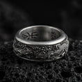 Load image into Gallery viewer, Oxidized phoenix engraved spinner fidget wedding band ring photographed on volcanic rock highlighting mythological rebirth symbolism and deep relief texture