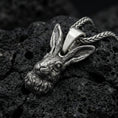 Load image into Gallery viewer, Oxidized rabbit head pendant on textured volcanic rock, macro close-up, detailed fur and ears, dark premium studio lighting