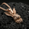 Load image into Gallery viewer, Rose gold plated rabbit jewelry pendant on volcanic rock, premium macro product photo, detailed hare ears and facial features
