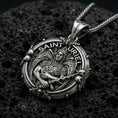 Load image into Gallery viewer, Oxidized Saint Uriel pendant on textured volcanic rock, macro close-up, angel warrior medallion detail, premium studio lighting