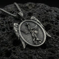 Load image into Gallery viewer, Oxidized Saint Michael archangel pendant on textured volcanic rock, macro close-up, oval medallion with wing accents, premium studio lighting
