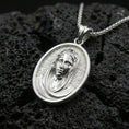 Load image into Gallery viewer, Polished silver Veiled Madonna necklace pendant on black volcanic stone background, crisp oval frame and veil texture, high-end product shot
