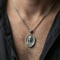 Load image into Gallery viewer, Oxidized Veiled Madonna pendant necklace worn on neck, lifestyle close-up on dark outfit, oval medallion centered