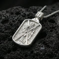 Load image into Gallery viewer, Polished silver Saint Andrew dogtag pendant necklace on black volcanic stone, crisp rectangular frame and patterned background, high-end product photo