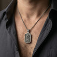 Load image into Gallery viewer, Oxidized Saint Andrew dog tag pendant necklace worn on neck, lifestyle close-up with dark outfit, pendant centered and clear