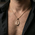 Load image into Gallery viewer, Rose gold plated Saint Andrew oval medallion pendant necklace worn on neck, dark clothing lifestyle shot, oval pendant in sharp focus