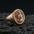 Load image into Gallery viewer, Rose gold plated Medusa ring featuring gorgon head relief and Greek key frame on volcanic rock backdrop