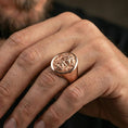 Load image into Gallery viewer, Oval Odin signet ring in a rose gold plated finish on finger, detailed Norse god face relief, lifestyle wear photo