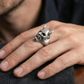 Load image into Gallery viewer, Sterling silver undead oni mask ring in an oxidized finish worn on finger, horned Japanese yokai skull detail visible, lifestyle hand close-up