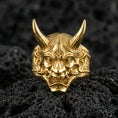 Load image into Gallery viewer, Japanese oni mask ring in a gold plated finish on volcanic rock, horned demon relief with fierce expression, luxury macro product image
