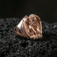 Load image into Gallery viewer, Rose gold plated griffin signet ring showcasing protective winged creature design and refined sculptural texture, sharp close-up on volcanic rock