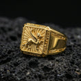 Load image into Gallery viewer, Gold plated gryphon signet ring with high-relief winged creature motif and ornate engraved sides, premium studio macro on black volcanic rock surface
