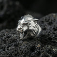 Load image into Gallery viewer, Polished silver werewolf signet ring featuring fierce wolf head sculpture and detailed fur texture, centered close-up on dark porous volcanic stone