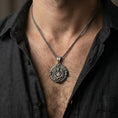 Load image into Gallery viewer, Oxidized Saint Gabriel pendant worn on neck on a braided chain, centered chest framing, moody lifestyle studio shot