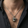 Load image into Gallery viewer, Oxidized sterling silver dragon pendant worn on neck on a braided chain, centered chest framing, moody lifestyle studio shot