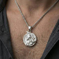 Load image into Gallery viewer, Polished silver Norse warrior medallion necklace worn on neck, close lifestyle crop, clear helmet relief and border pattern detail