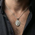 Load image into Gallery viewer, Polished silver Guadalupe medallion necklace worn on neck, close lifestyle crop, clear Marian relief and oval frame details