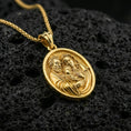 Load image into Gallery viewer, Gold plated Holy Family pendant on porous volcanic rock backdrop, devotional oval medal with detailed family relief, high-contrast lighting
