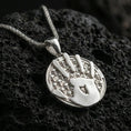 Load image into Gallery viewer, Polished silver Dark Brotherhood handprint pendant necklace on dark volcanic stone, crisp raised emblem and detailed skull texture, premium close-up