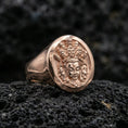 Load image into Gallery viewer, Rose gold plated spiritual signet ring on volcanic stone, oval signet face with multi-faced deity relief and sculpted border