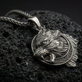 Load image into Gallery viewer, Oxidized Fenrir wolf pendant necklace photographed on volcanic rock with detailed Norse beast relief and runic frame