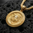 Load image into Gallery viewer, Gold plated Medusa amulet necklace showcased on volcanic rock as a symbol of protection, power, and feminine strength