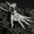 Load image into Gallery viewer, Polished silver Elden Ring inspired Hand of Maliketh pendant displayed on volcanic stone background highlighting sharp talon detail