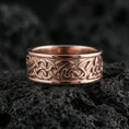 Load image into Gallery viewer, Rose gold plated Celtic knot ring presented on volcanic rock surface with warm metallic tone and intricate interwoven pattern detail
